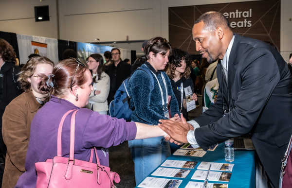 Photo of people shaking hands at an exhibit booth at the FMEA Conference